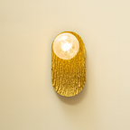 Gold wall sconce with a light bulb on a beige background