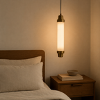 Pendant light hanging above a bed in a bedroom setting