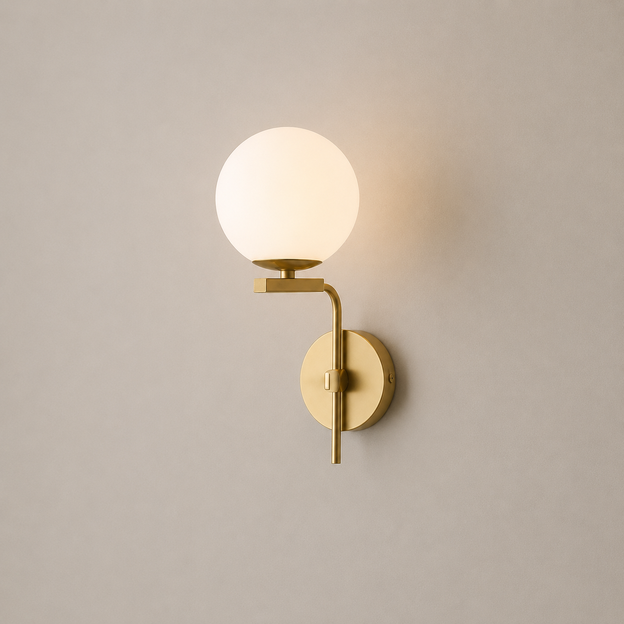 Wall-mounted lamp with a round glass shade and gold fixture on a plain wall.