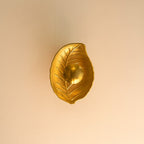 Gold leaf-shaped decorative object on a beige background