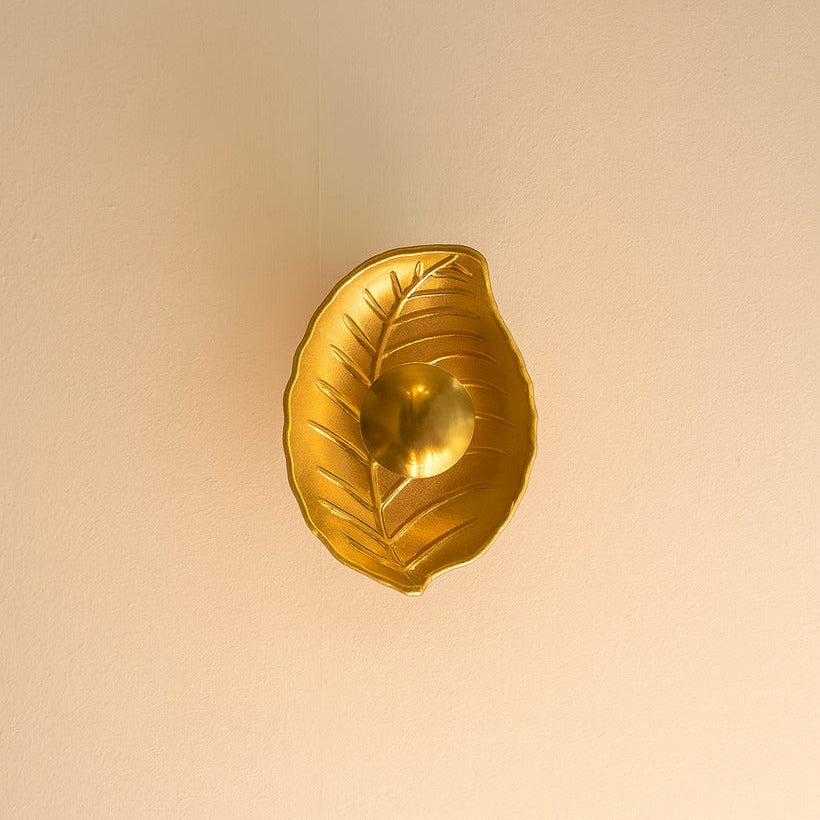 Gold leaf-shaped decorative object on a beige background