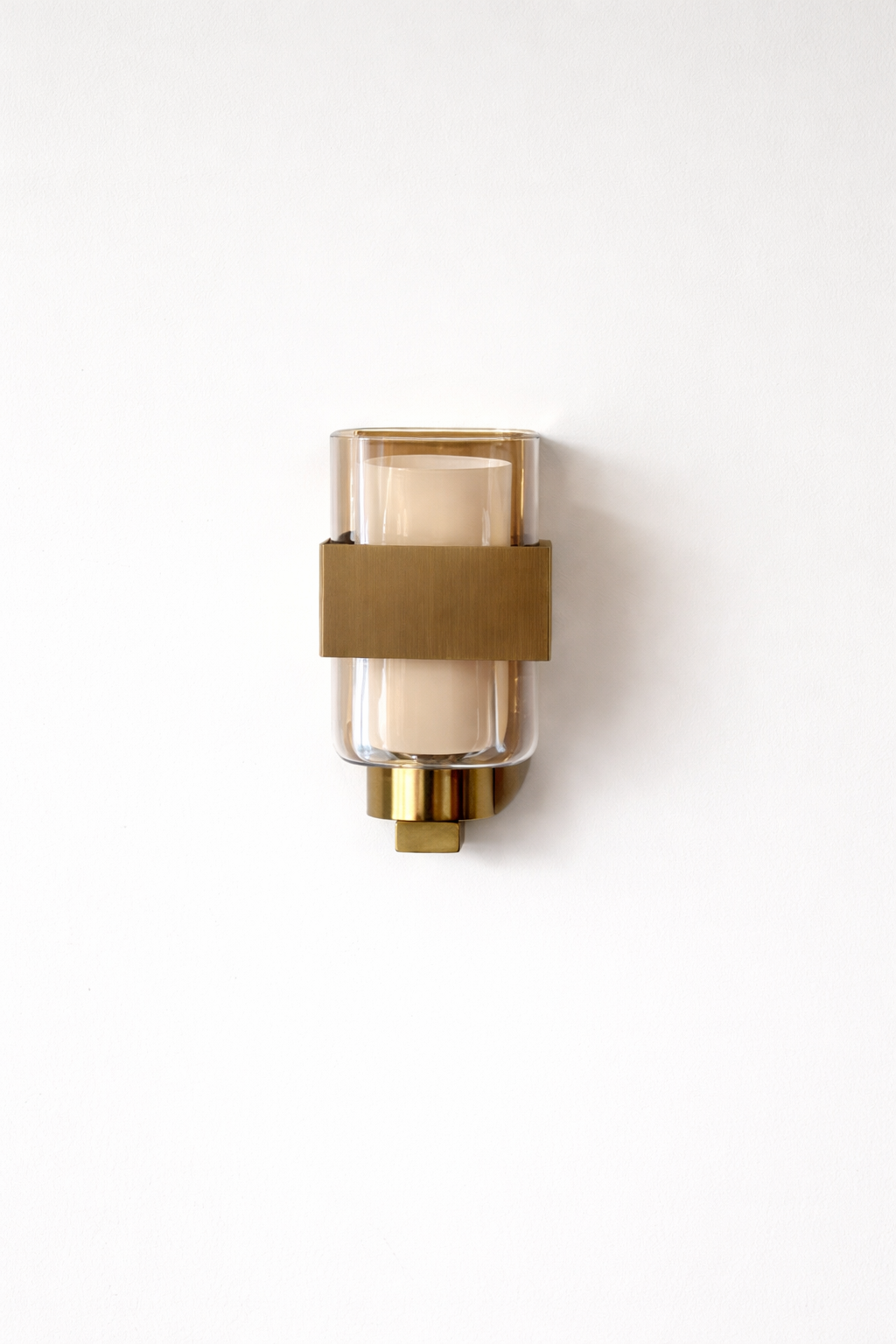 Brass wall sconce with glass shade on a white background
