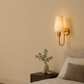 Bedroom with a wall-mounted lamp, nightstand, and plant