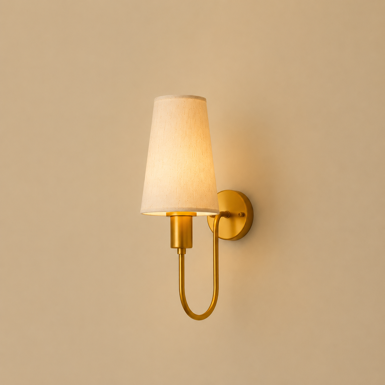 Gold wall sconce with a white lampshade on a beige wall