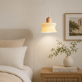 Bedroom with a pendant light, bed, and decorative items on a nightstand.