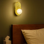 Bedroom scene with a wall sconce casting a warm glow on a bed and nightstand.