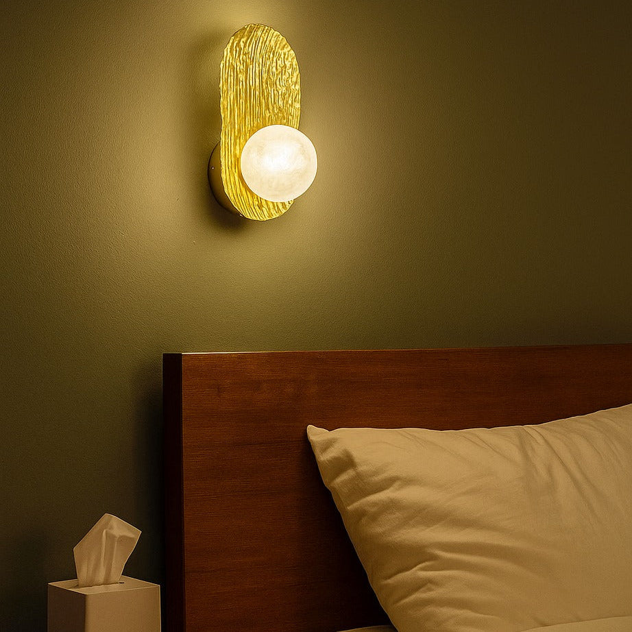 Bedroom scene with a wall sconce casting a warm glow on a bed and nightstand.