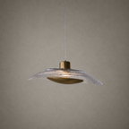 Pendant light with textured glass shade and brass fixture on a neutral background