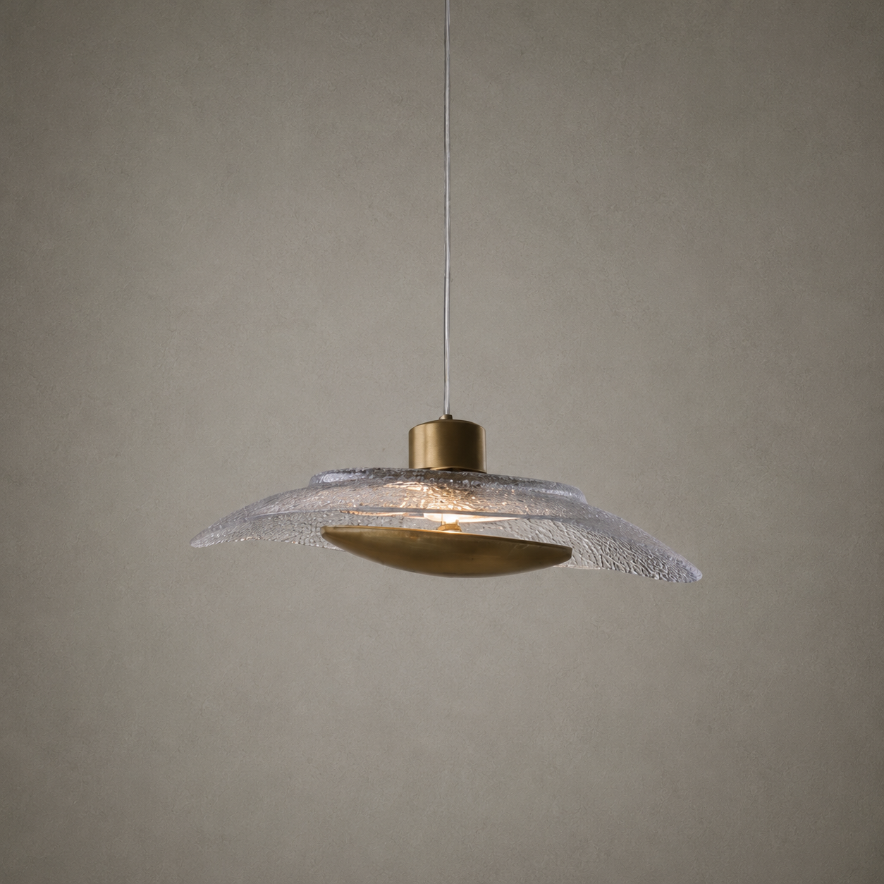 Pendant light with textured glass shade and brass fixture on a neutral background