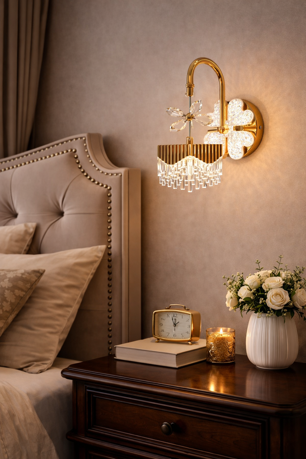 Decorative wall sconce above a nightstand with a clock, books, and flowers.