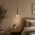 Modern bedroom with a pendant light, bed, and decorative elements.