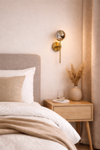Neatly made bed with beige blanket and pillows in a bedroom setting.