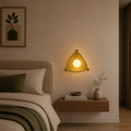 Nestled corner of a bedroom with a bed, wall-mounted lamp, and small table with decor items.