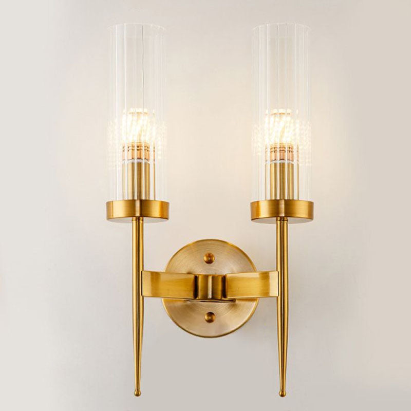 Gold wall sconce with clear glass shades on a white wall