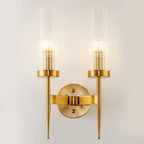 Gold wall sconce with clear glass shades on a white wall