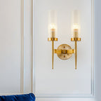 Gold wall sconce with two lights on a white wall.
