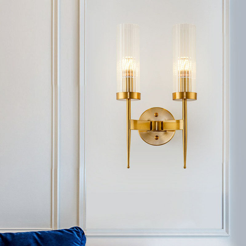 Gold wall sconce with two lights on a white wall.