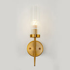 Gold wall sconce with clear glass shade on a light gray background