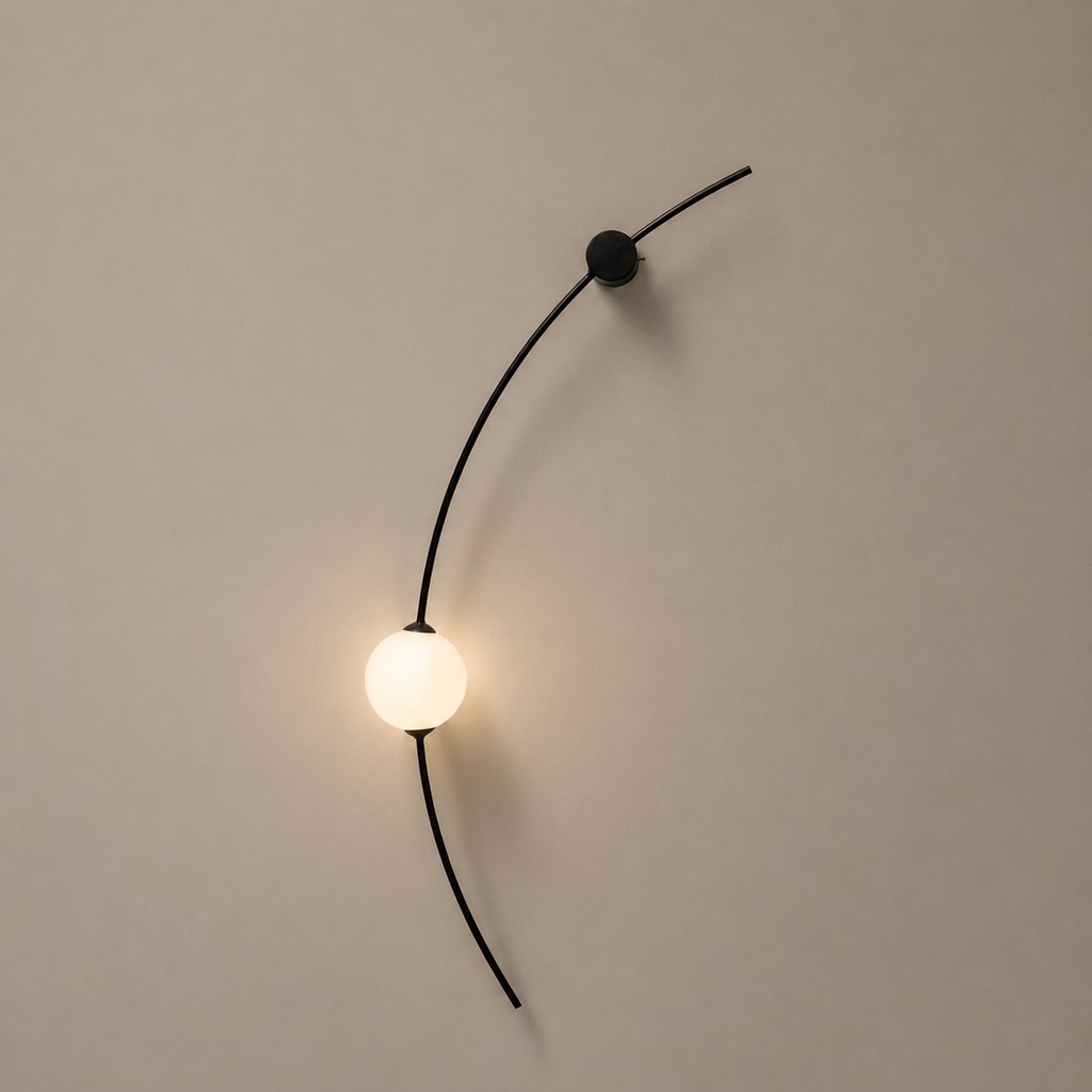 Modern wall lamp with a curved black cable and round bulb on a beige wall.
