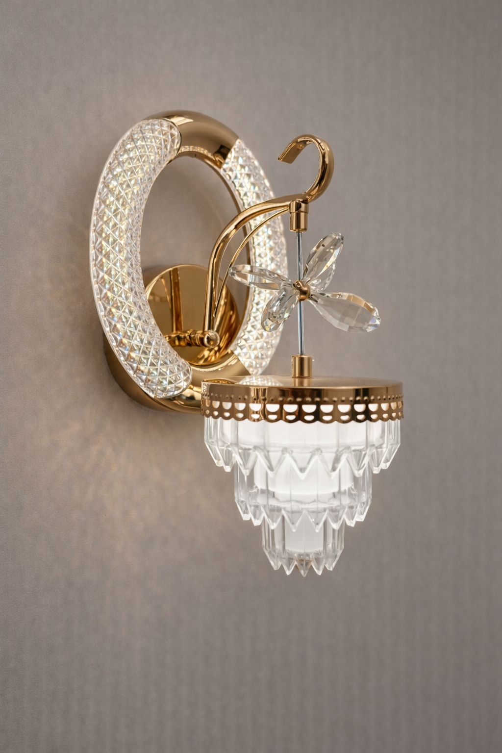 Decorative wall light fixture with gold and crystal design on a gray background