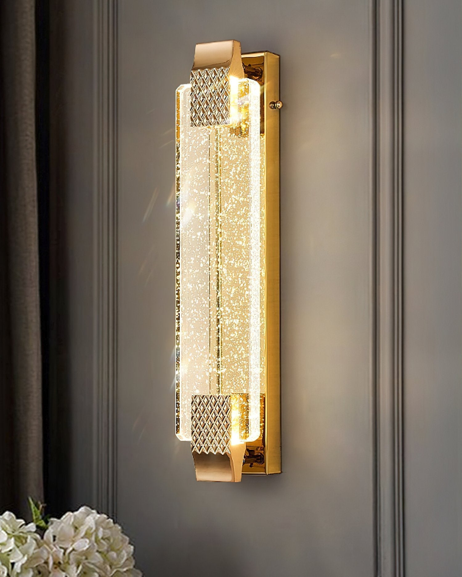 Gold wall sconce with crystal design on a gray wall