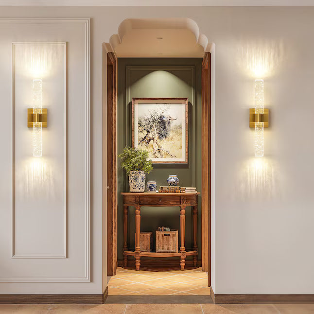 Decorative interior with wall sconces, a console table, and framed artwork.