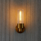 Wall-mounted light fixture with a gold finish on a wooden wall.