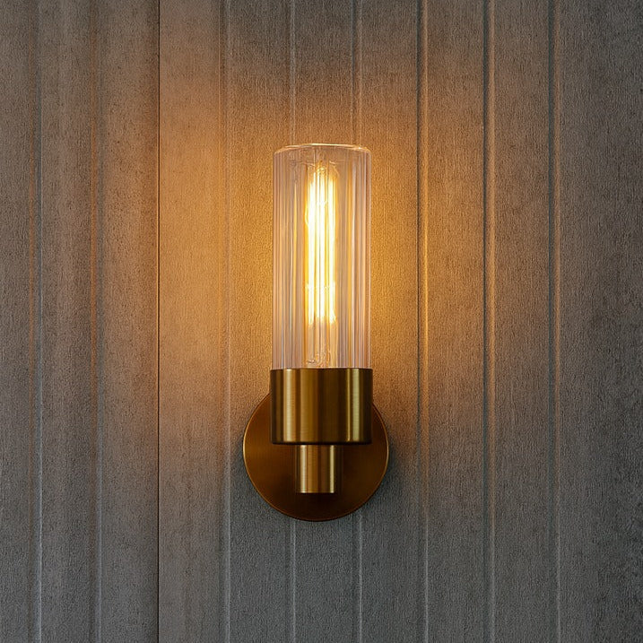Wall-mounted light fixture with a gold finish on a wooden wall.