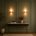 Decorative interior setting with wall lights, a console table, and plants.