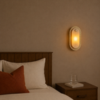 Bedroom with wooden headboard, pillows, and wall-mounted light fixture.
