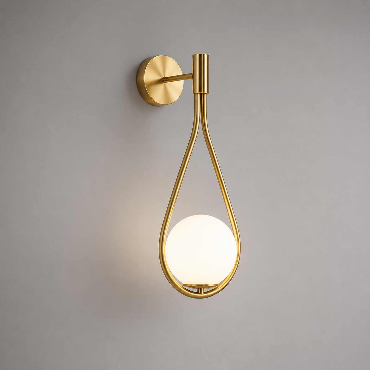 Gold wall-mounted light fixture with a white bulb on a gray background