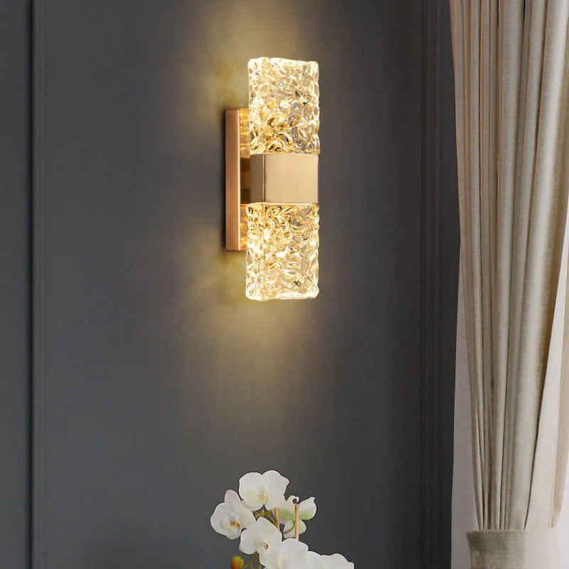 Decorative wall light fixture on a dark wall with a curtain and plant in the background