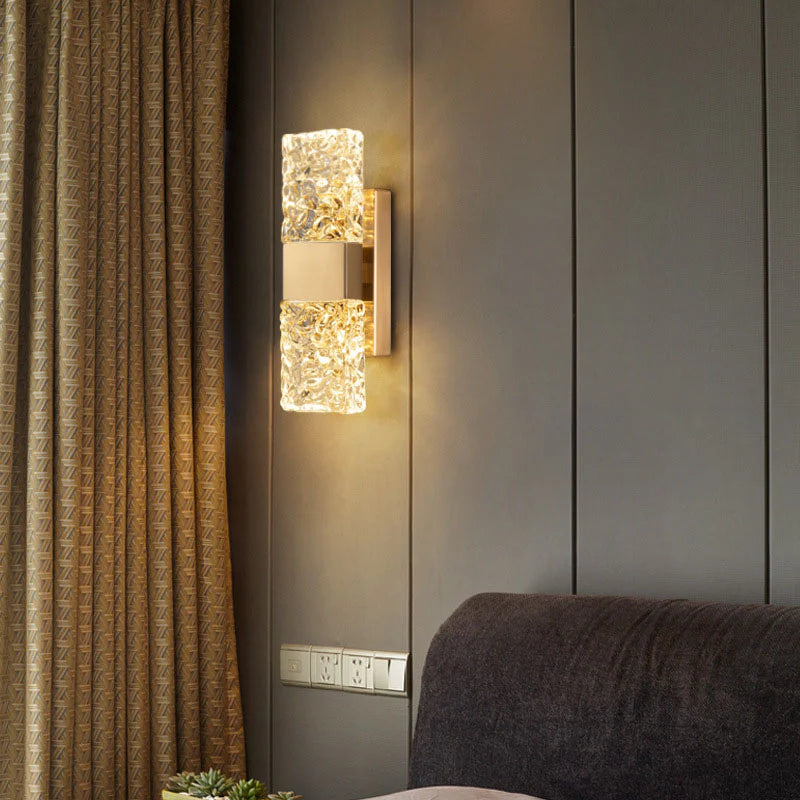 Modern wall sconce with decorative glass panels on a gray wall next to a curtain.