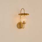 Gold wall-mounted lamp with glass shade on a beige wall
