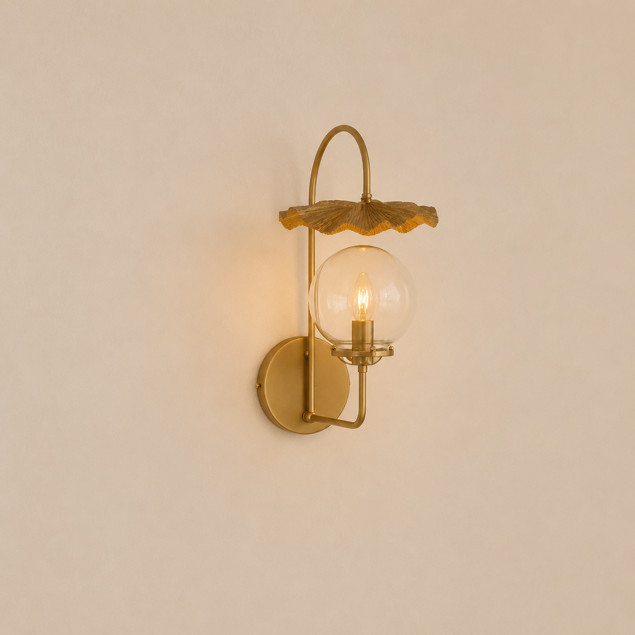 Gold wall-mounted lamp with glass shade on a beige wall