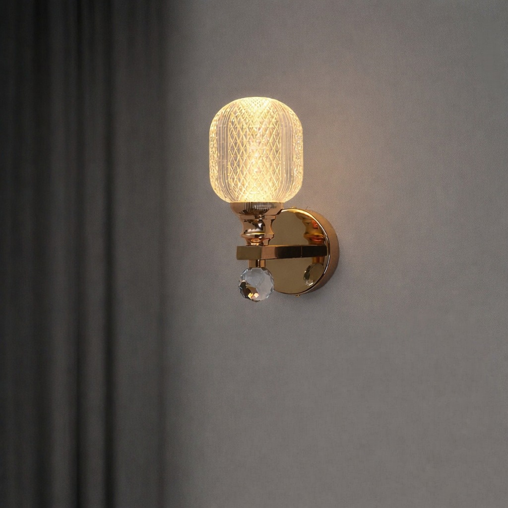 Wall-mounted light fixture with gold finish and textured glass shade on a gray wall.