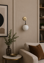 Modern wall sconce with a white globe light fixture in a living room setting.