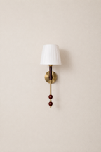 Wall-mounted lamp with a white shade and decorative elements on a beige wall