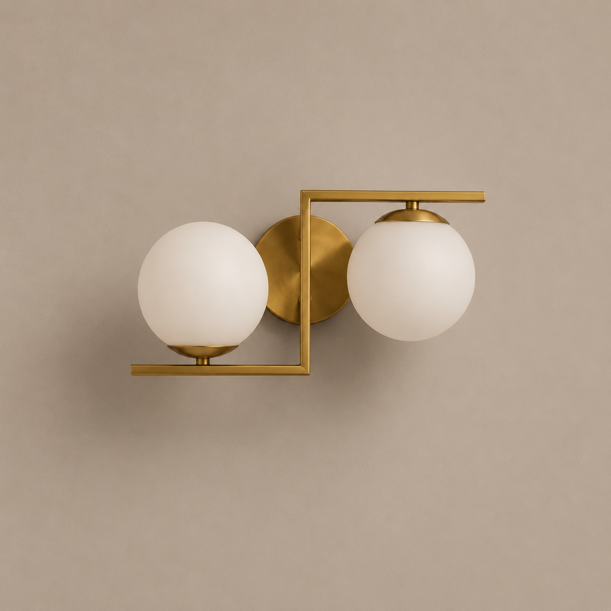 Gold wall sconce with two white glass globes on a beige wall.