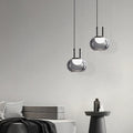 Modern pendant lights hanging against a gray wall with minimal decor.