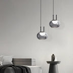Modern pendant lights hanging against a gray wall with minimal decor.