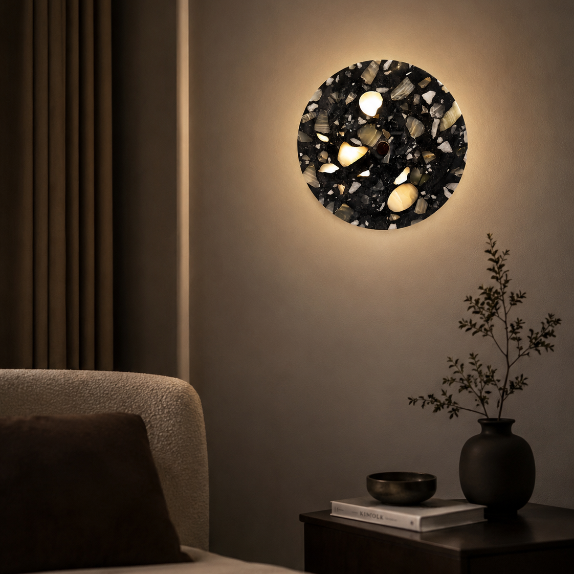 Round wall light fixture on a neutral wall with a vase and books on a side table.
