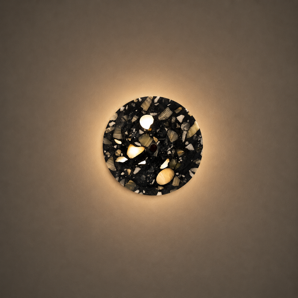 Round wall light fixture with a decorative black and white pattern on a beige wall.