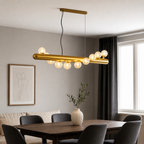 Modern dining room with a gold pendant light fixture, wooden table, and gray chairs.