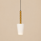 Pendant light with gold bead detailing on a beige background