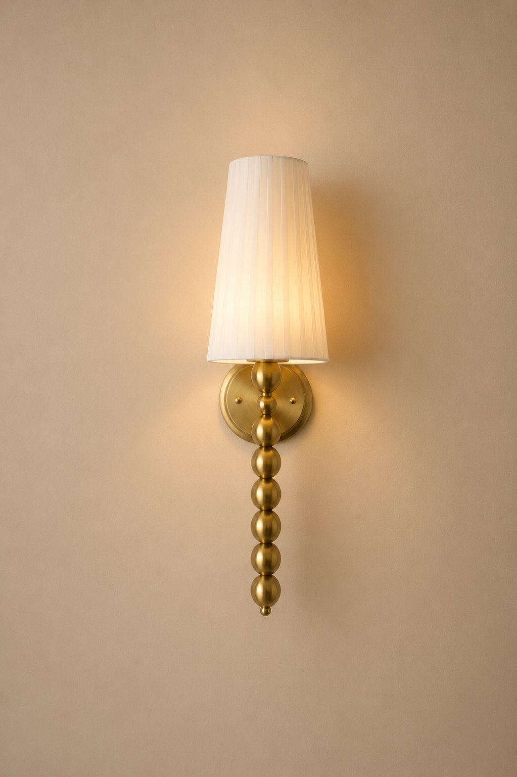 Gold wall sconce with a white lampshade on a beige wall