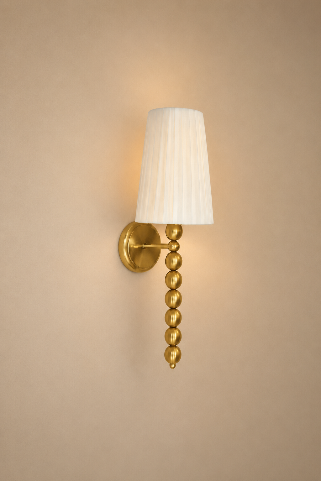 Wall sconce with gold fixture and white lampshade on a beige wall