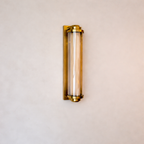 Wall-mounted light fixture with gold frame and clear glass on a beige wall.