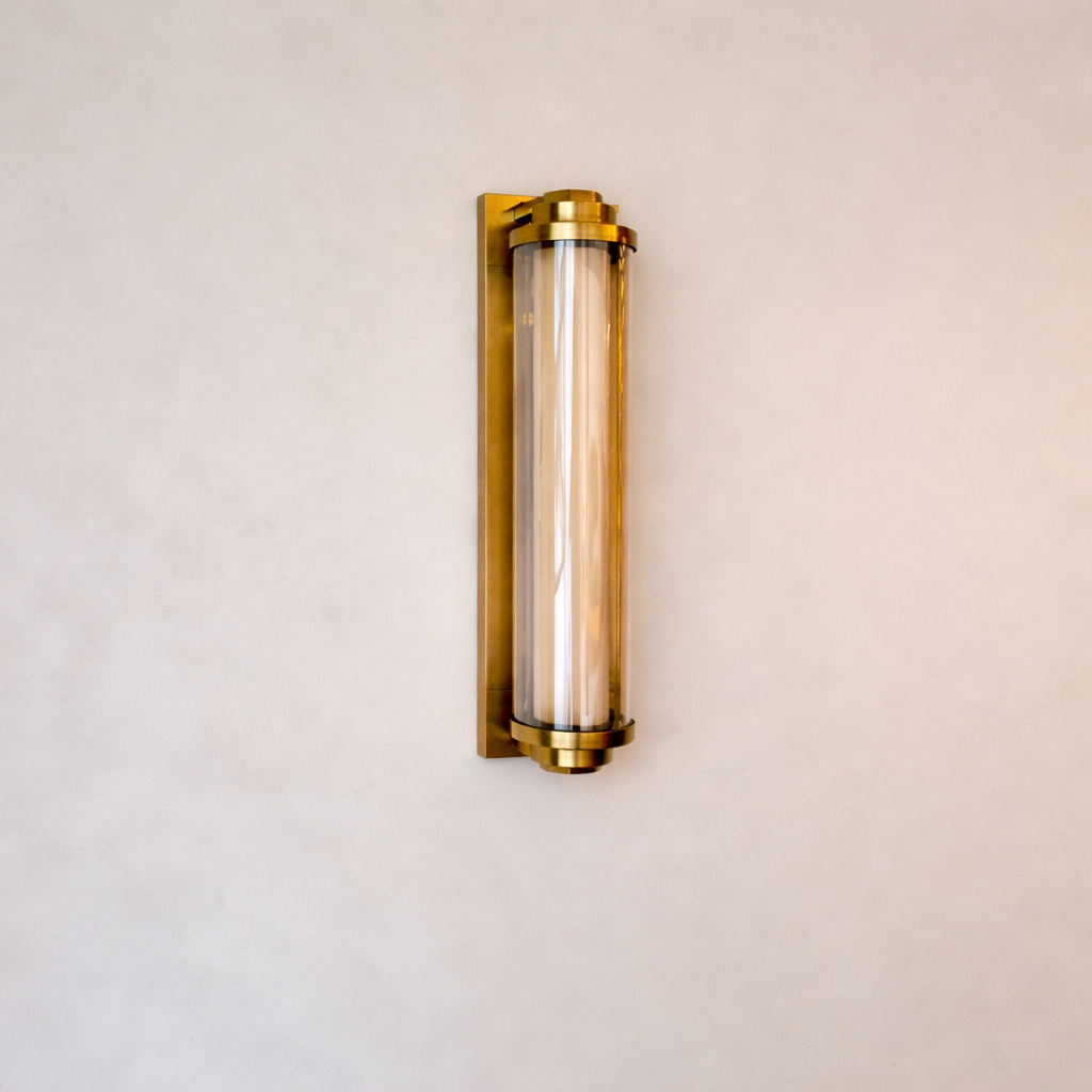 Wall-mounted light fixture with gold frame and clear glass on a beige wall.
