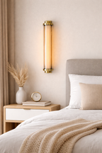 Neatly made bed with a nightstand and wall sconce in a bedroom setting